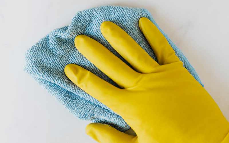 IEA Medical - Eine Hand mit gelbem handschuh wischt mit einem blauen Tuch über eine Oberfläche